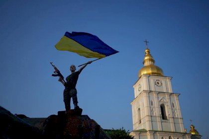 A woman with Ukrainian flag on a destroyed Russian tank in Kyiv.jpg