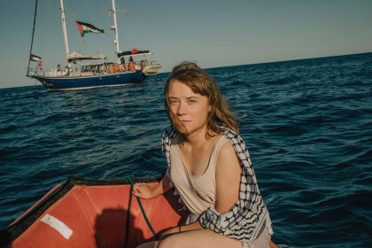 a woman sitting on the back of a boat in the ocean next to a sailboat.jpg