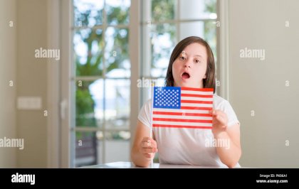 down-syndrome-woman-at-home-holding-flag-of-usa-scared-in-shock-with-a-surprise-face-afraid-and-excited-with-fear-expression-PK06A1.jpg